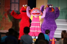 Elmo and his friends console Katie, a new member to the Sesame Street cast, during a USO performance of Sesame Street Live aboard Marine Corps Air Station New River, April 28. Katie, a military child, was distraught over moving to a new town before the Sesame Street cast showed her and the audience how she can cope with her new life.
