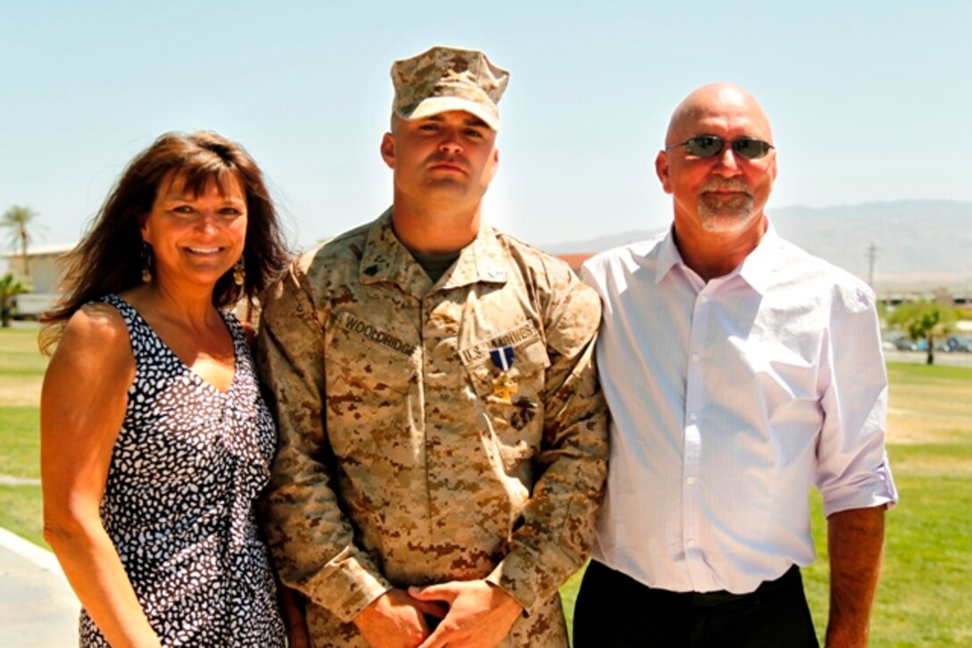 Sgt. Clifford Wooldridge, combat weapons instructor, Marine Corps Security Forces Regiment, Chesapeake, Va., stands with his mother and father, wearing the Navy Cross medal he earned for combat actions in Helmand province, Afghanistan, while attached to 3rd Battalion, 7th Marine Regiment, in 2010. (U.S. Marine Corps photo by Cpl. Sarah Dietz)::r::::n::::r::::n::