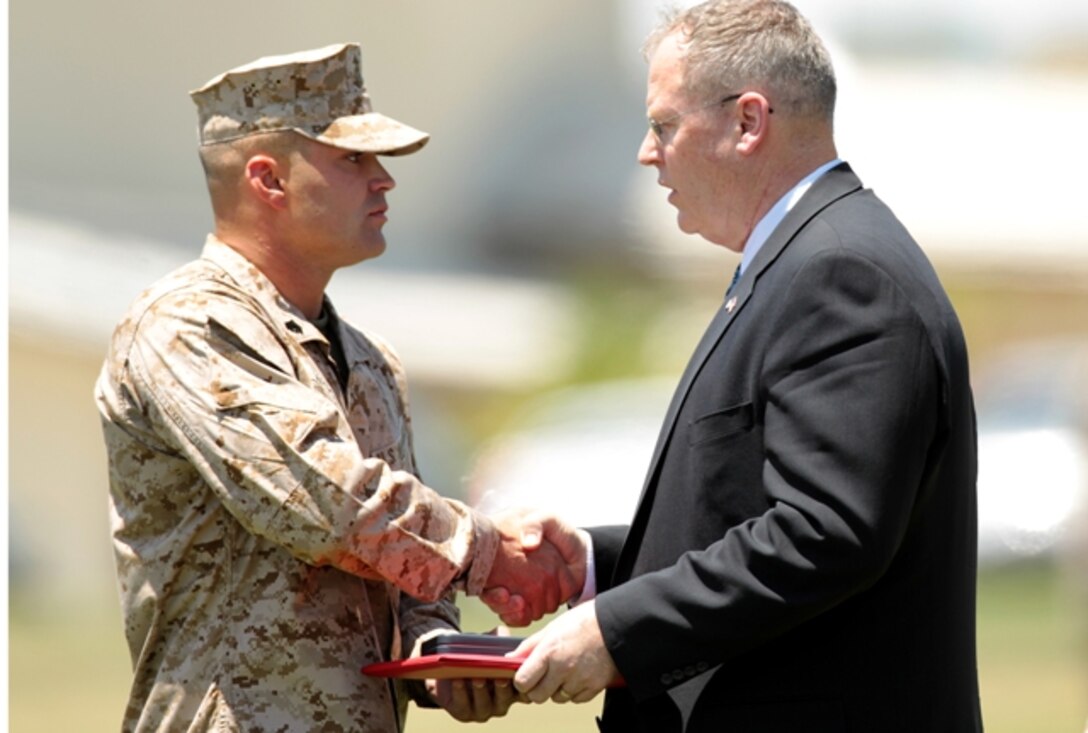 Sgt. Clifford Wooldridge, combat weapons instructor, Marine Corps Security Forces Regiment, Chesapeake, Va., shakes the hand of Undersecretary of the Navy Robert O. Work, while receiving the Navy Cross Medal May 18 at Lance Cpl. Torrey L. Gray Field. He earned the medal for combat actions in Helmand province, Afghanistan, while attached to 3rd Battalion, 7th Marine Regiment, in 2010.