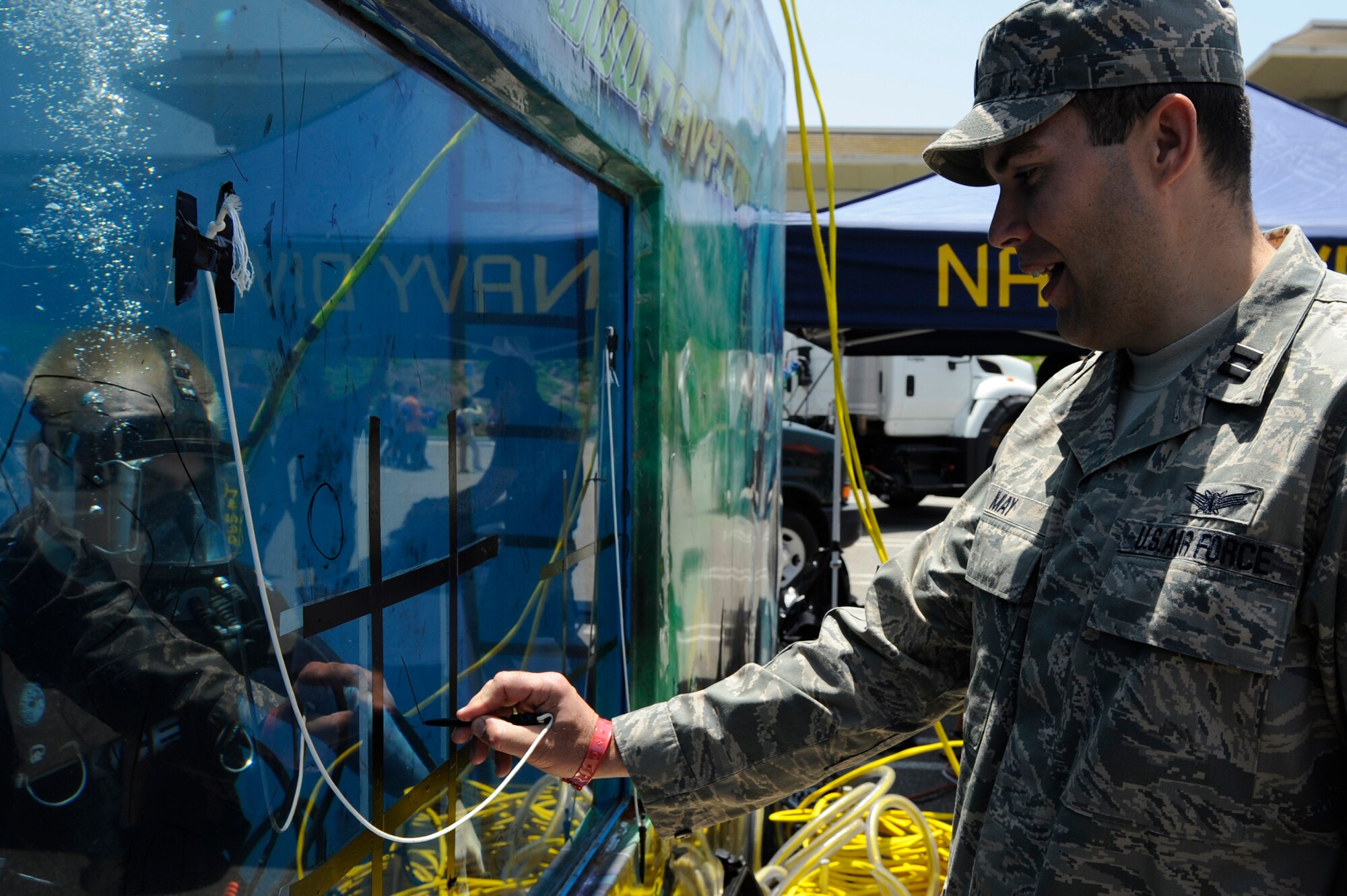 TORRANCE, Calif. --Capt. Michael May, a 30th Operations Group deputy chief of standardization and evaluation, plays tic-tac-toe with a Navy diver at the Navy Diver Tank display during the 53rd Annual Armed Forces Day here Friday, May 18, 2012. Military displays varied from rockets to tanks and were open for the public. (U.S. Air Force photo/Staff Sgt. Levi Riendeau) 
