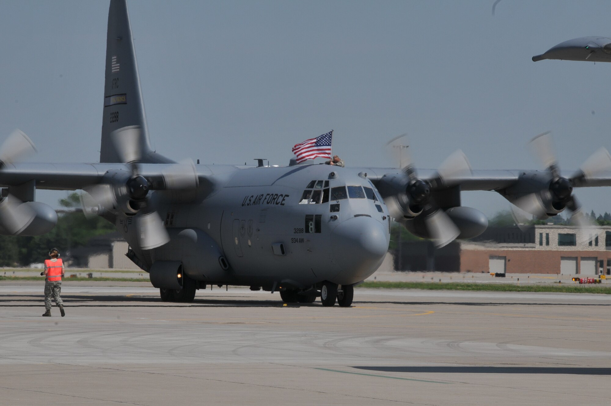 Airmen hold up the American flag as their C-130 Hercules taxis up to the hangar where families await their arrival at the Minneapolis-St. Paul Air Reserve Station, Minn. The 934th Airlift Wing Airmen have been deployed since early 2012.  (U.S. Air Force Photo/Tech. Sgt. Bob Sommer)