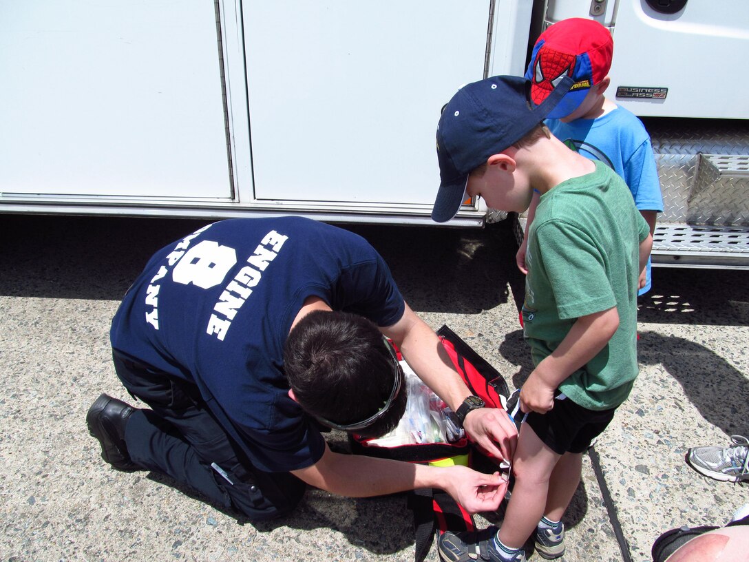 Tom Longllis, an emergency medical technician from Prince George County puts a bandage on four year old Sam Rockwell's knee during the Joint Service Open House. This year's Joint Service Open House celebrates the Centennial of Marine Corps Aviation. JSOH affords the public and opportunity to meet the men and women of the Armed Forces while viewing over 100 static displays and 19 aerial demonstration teams. (Air Force Photo/Melanie Moore)