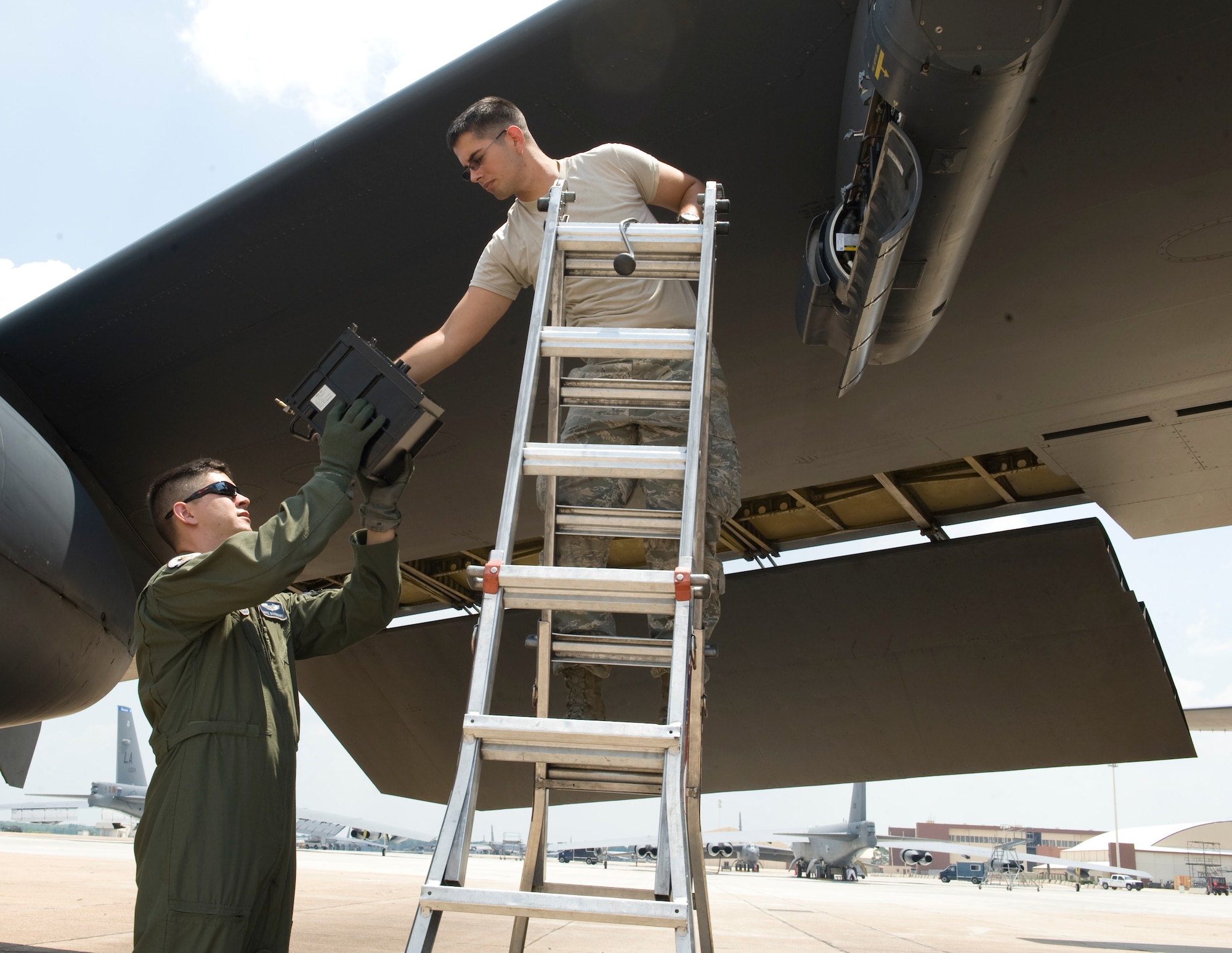 Capt. Nate Barnhart, 20th Bomb Squadron radar navigator instructor, reaches for a piece of equipment from an Airman from the 20th Aircraft Maintenance Unit on Barksdale Air Force Base, La., May 17. The crew replaced a piece of equipment from the LITENING Advanced Targeting pod. Each member of the Aircrew checks specific items before each flight. If they find anything wrong with the aircraft, they will contact a crew chief to fix the problem. (U.S. Air Force photo/Airman 1st Class Benjamin Gonsier)(RELEASED)
