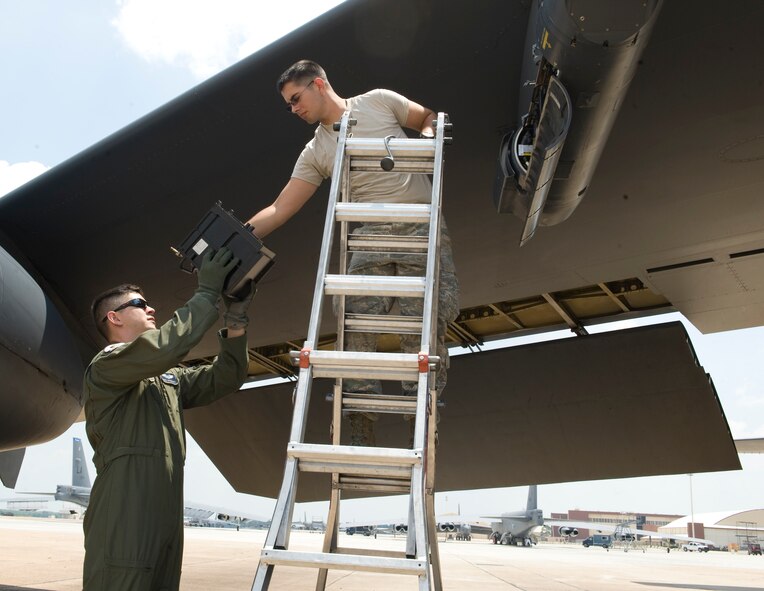 Capt. Nate Barnhart, 20th Bomb Squadron radar navigator instructor, reaches for a piece of equipment from an Airman from the 20th Aircraft Maintenance Unit on Barksdale Air Force Base, La., May 17. The crew replaced a piece of equipment from the LITENING Advanced Targeting pod. Each member of the Aircrew checks specific items before each flight. If they find anything wrong with the aircraft, they will contact a crew chief to fix the problem. (U.S. Air Force photo/Airman 1st Class Benjamin Gonsier)(RELEASED)