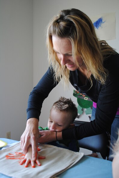 Tiffany Taylor helps her son Chase, 3, put an orange handprint on a tote in celebration of Mother's Day at the Lifeworks House on May 10. (U.S. Air Force photo/Airman 1st Class Katrina Heikkinen)