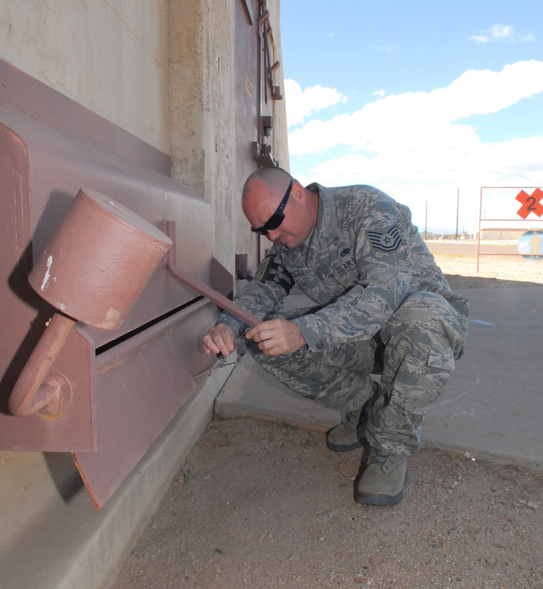Tech. Sgt. Tony Rudicill, 56th Fighter Wing Weapons Safety NCO, inspects a fire preventing vent on a munitions storage structure here April 26. The fusible links on the vent release the cover and prevent fire from entering the building.  (U.S. Air Force photo by Chief Master Sgt. Larry Schneck)