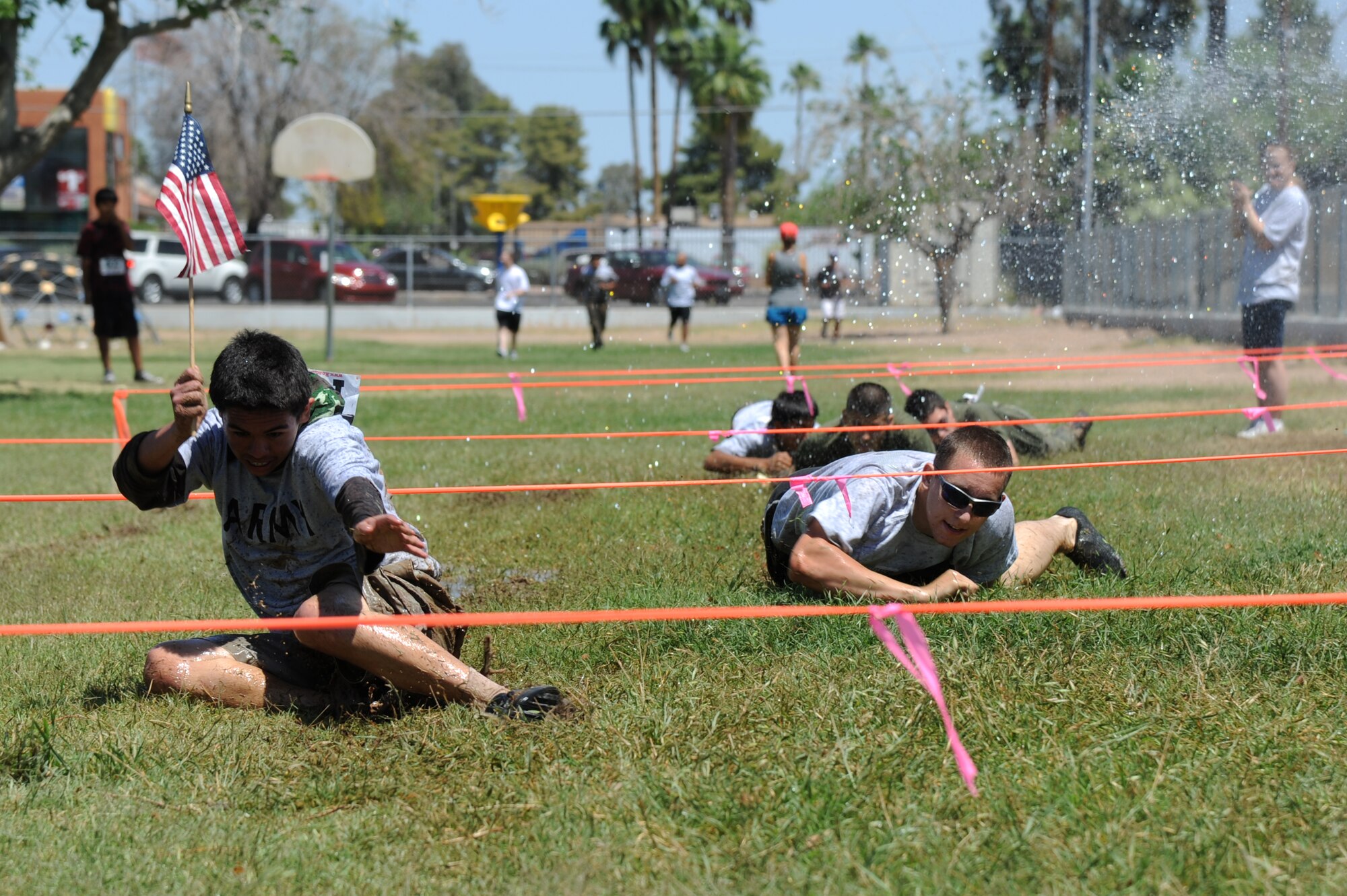 Airman 1st Class Henry Eichorn, 62nd Aircraft Maintenance Unit, low crawls with Cartwright Elementary students during the Yee-haw Fun Run. Lorain Marquez, a 5th grade teacher at Cartwright, came up with the idea of the fun run after participating in Arizona Spartan Sprint in February.  (U.S. Air Force photo by Senior Airman Sandra Welch)