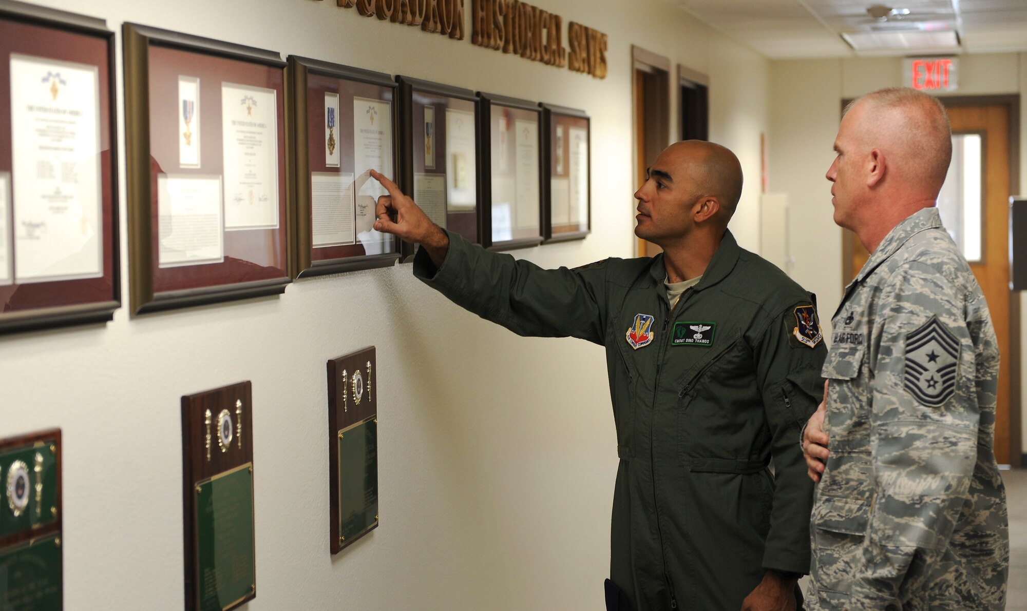 U.S. Air Force Chief Master Sgt. Konstantinos Thanos, 66th Rescue Squadron chief enlisted manager, shows a memorial wall to Chief Master Sgt. Frank Batten, 23d Wing command chief, during his visit to Nellis Air Force Base, Nev., May 8, 2012. The 66th RQS is a geographically separated unit assigned to the 23d Wing, Moody Air Force Base, Ga. (U.S. Air Force photo by Staff Sgt. Ciara Wymbs/Released)