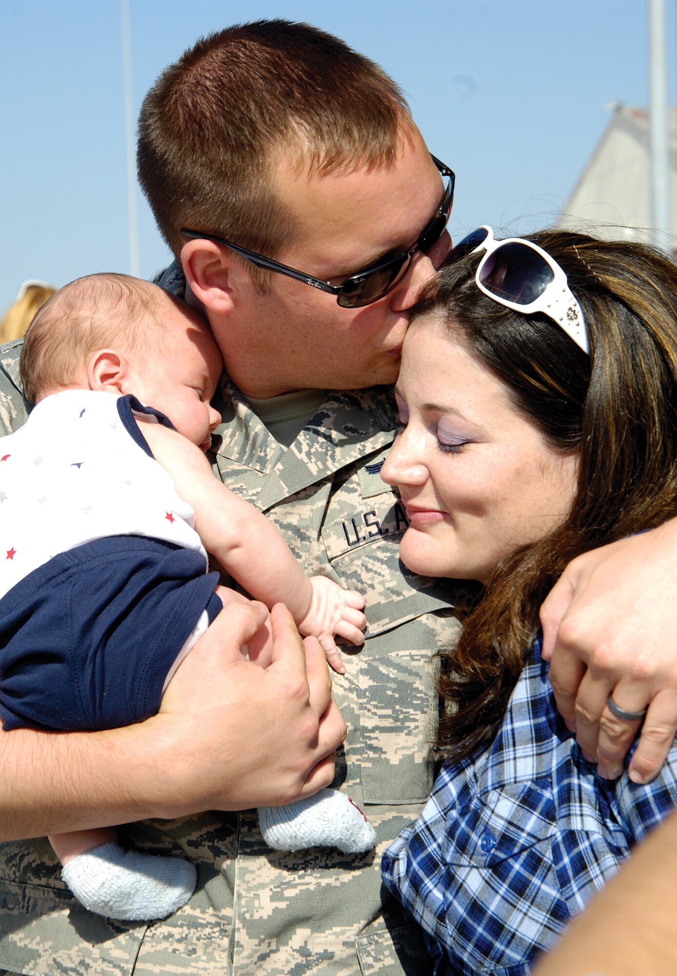 Staff Sgt. Denny Rindal cuddles his two-month old son, Grayson, and tenderly kisses his wife, Shannon, minutes after returning to Tinker following a six-month deployment.  Mom and three-year-old son Dawson waited May 15 with Grayson and a sign speaking for the youngest who was born while the sergeant was supporting operations in Afghanistan. Approximately 150 552nd Air Control Wing Airmen stream off a jet May 15 onto a Tinker ramp, greeted by commanders and the applause and cheers of waiting friends and family. The Airmen returned from a six-month deployment to Southwest Asia supporting ongoing operations in Afghanistan.  (Air Force photo by Margo Wright)