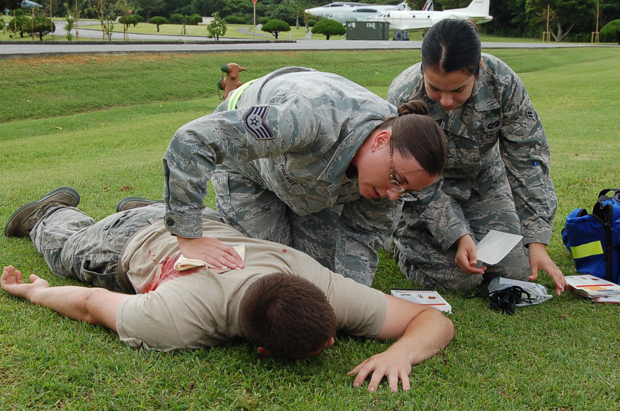 Staff Sgt. Michelle Prevot, 18th Wing Judge Advocate paralegal, checks for a response from an injured member while Airman 1st Class Lezette Orellana, 18th Wing Judge Advocate military justice paralegal, checks her Airmen's Manual during a local operational readiness exercise scenario on Kadena Air Base, Japan, May 15, 2012. LOREs are conducted on a regular basis to test the base's ability to operate in combat conditions. (U.S. Air Force photo/Senior Master Sgt. Daniel Kazumura)