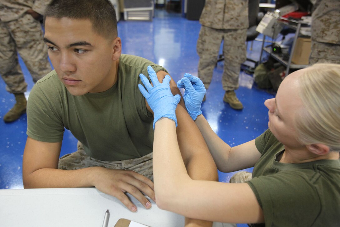 Petty Officer 3rd Class Sarah Johnson, corpsman, Marine Medium Helicopter Squadron 364 (Rein.), 15th Marine Expeditionary Unit, vaccinates Lance Cpl. Christopher M. Carino, an airframe mechanic from the same unit, during the three-week Composite Training Unit Exercise, July 19. Corpsmen from the 15th MEU and the Peleliu Amphibious Ready Group began working together in the USS Peleliu’s medical center to ensure servicemembers are medically ready for deployment later this year.