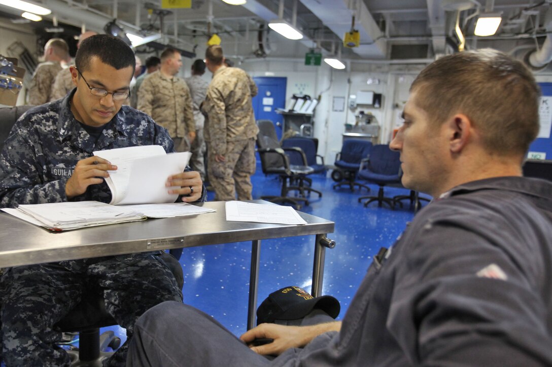 Petty Officer 3rd Class Omar Aguilar, hospital corpsman, USS Peleliu, reviews the medical paperwork of Petty Officer 2nd Class William Jones, hall maintenance technician, USS Peleliu, during the three-week Composite Training Unit Exercise, July 19. Corpsmen from the 15th MEU and the Peleliu Amphibious Ready Group began working together in the USS Peleliu’s medical center to ensure service members are medically ready for deployment later this year.
