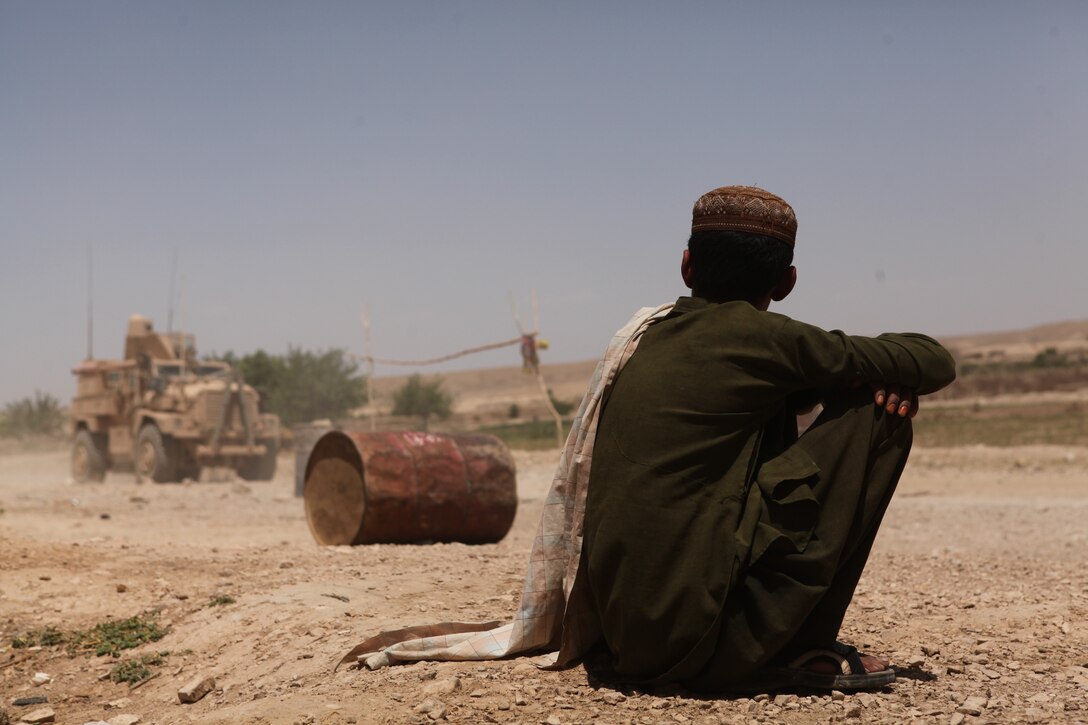 An Afghan child watches a Marine convoy pass a bazaar here, May 19, 2012. Hundreds of Marines and Afghan National Army soldiers took part in Operation Sangin United Horizons, an operation aimed at disrupting insurgent activity throughout the region.