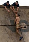 Volunteers Sgt. Nicholas J. Bynum and Staff Sgt. Clinton F. Firstbrook, both with Recruiting Station Twin Cities, help competitors up an obstacle named Everest during Tough Mudder Twin Cities May 20. Everest is a quarter pipe that is designed with teamwork in mind. Few can scale this obstacle without help from their fellow participants.