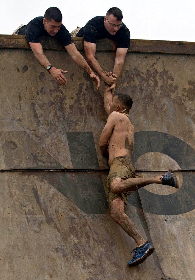 Volunteers Sgt. Nicholas J. Bynum and Staff Sgt. Clinton F. Firstbrook, both with Recruiting Station Twin Cities, help competitors up an obstacle named Everest during Tough Mudder Twin Cities May 20. Everest is a quarter pipe that is designed with teamwork in mind. Few can scale this obstacle without help from their fellow participants.