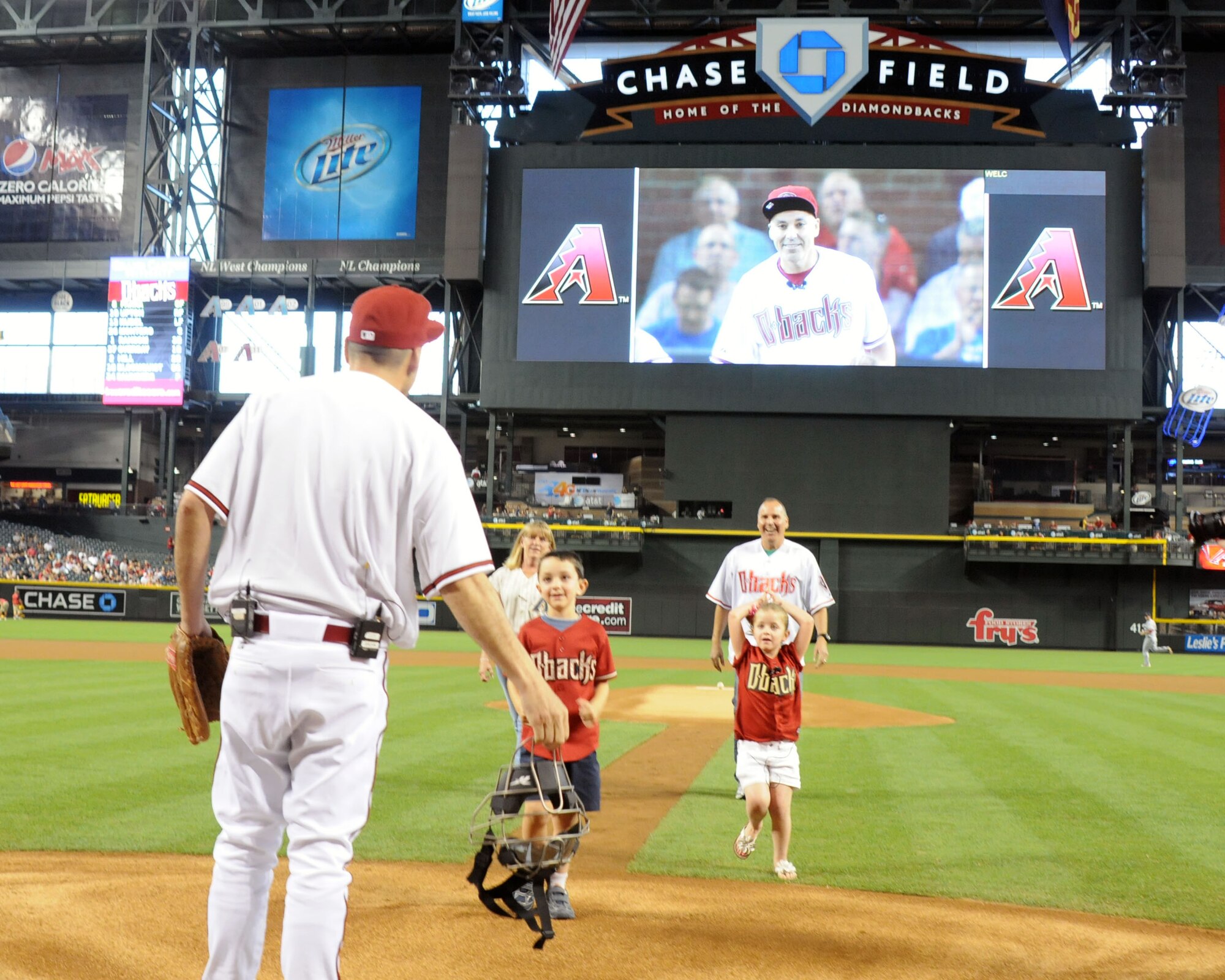 Lt. Col. Paul Aguirre, 161st Air Refueling Wing chief of staff, reveals himself to his children, Jackson and Alanna, after they threw the first pitch at the Diamondbacks game May 7, 2012. Jackson and Alanna thought their dad was still in Afghanistan where he had spent the last seven months serving with the Arizona Air National Guard. Colonel Aguirre and the Arizona Diamondbacks worked together via email while Colonel Aguirre was deployed to set up the surprise reunion. (U.S. Air Force photo by Tech. Sgt. Susan Gladstein/Released)