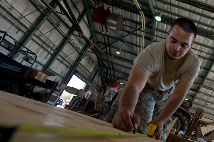 U.S. Army Spc. Luis Cobos, 264th Combat Sustainment Support Battalion, 82nd Sustainment Brigade parachute rigger, from Fort Bragg, Ga., measures and marks wood to be cut while rigging cargo for a Mobility Air Forces Exercise May 16, 2012, at Nellis Air Force Base, Nev. The U.S. Air Force Weapons School holds MAFEX twice a year to test the ability of weapons school students to plan and lead a massive "forced entry" operation using cargo aircraft based and launched from Air Force installations around the world. The students will lead mass formations of C-17 Globemaster III and C-130 Hercules aircraft, accompanied by fighters and other assets, in order to get joint forces on the ground in a simulated hostile county. (U.S. Air Force photo by Airman 1st Class Daniel Hughes)