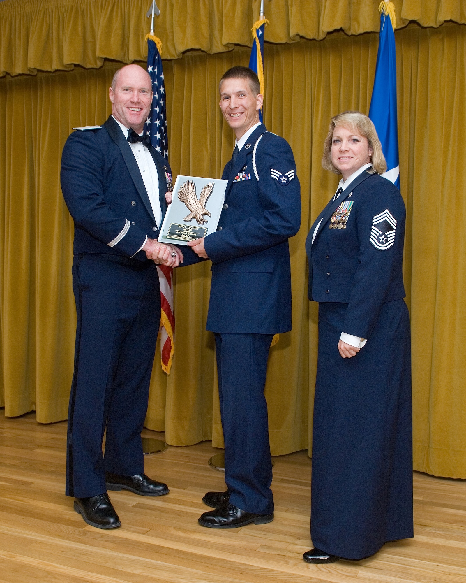 Brig. Gen. Robert C. Nolan II, Air Force Flight Test Center commander (left), presents Senior Airman Joseph A. Millstead, 412th Operations Support Squadron, with the John L. Levitow Award May 17 at the Airman Leadership School graduation held at Club Muroc. It is the school's most prestigious award presented to the top performer in each class. Chief Master Sgt. Lisa Richards of the 95th Medical Group and acting 95th Air Base Wing command chief also congratulated Millstead. (Air Force Photo by Edward Cannon)
