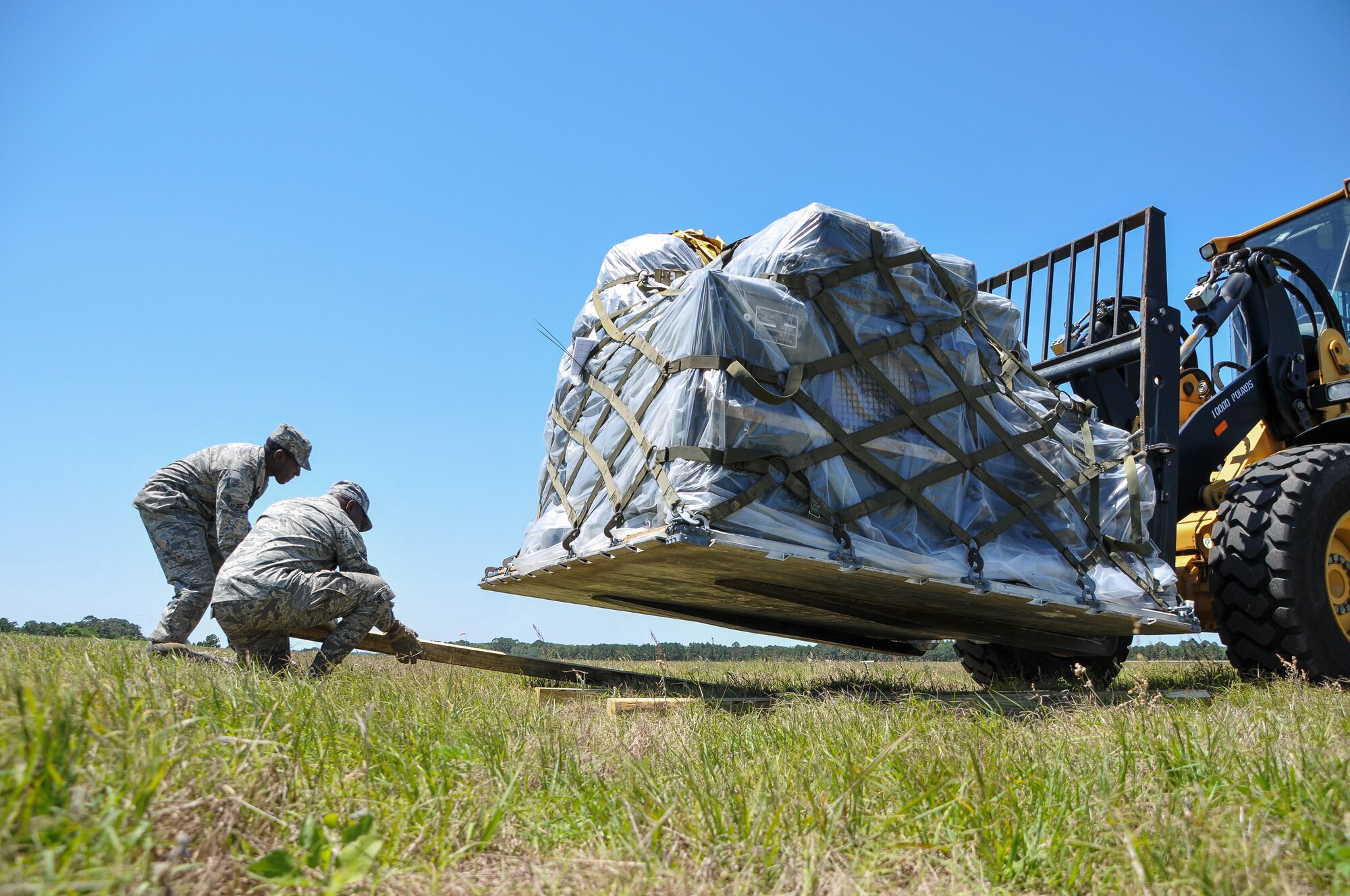 National Guard Staff Sgt. Dwain Whitehead and National Guard Airman 1st Class Peter Motovu of the 117th Air Control Squadron place dunnage underneath a pallet during annual field training at Amelia Island Airport, FL, April 24, 2012. By replacing convoy vehicles with pallets, the 117th ACS reduced the equipment transportation footprint from 40 to 20 C-17 Globemaster IIIs. (National Guard photo by Tech. Sgt. Charles Delano/Released)