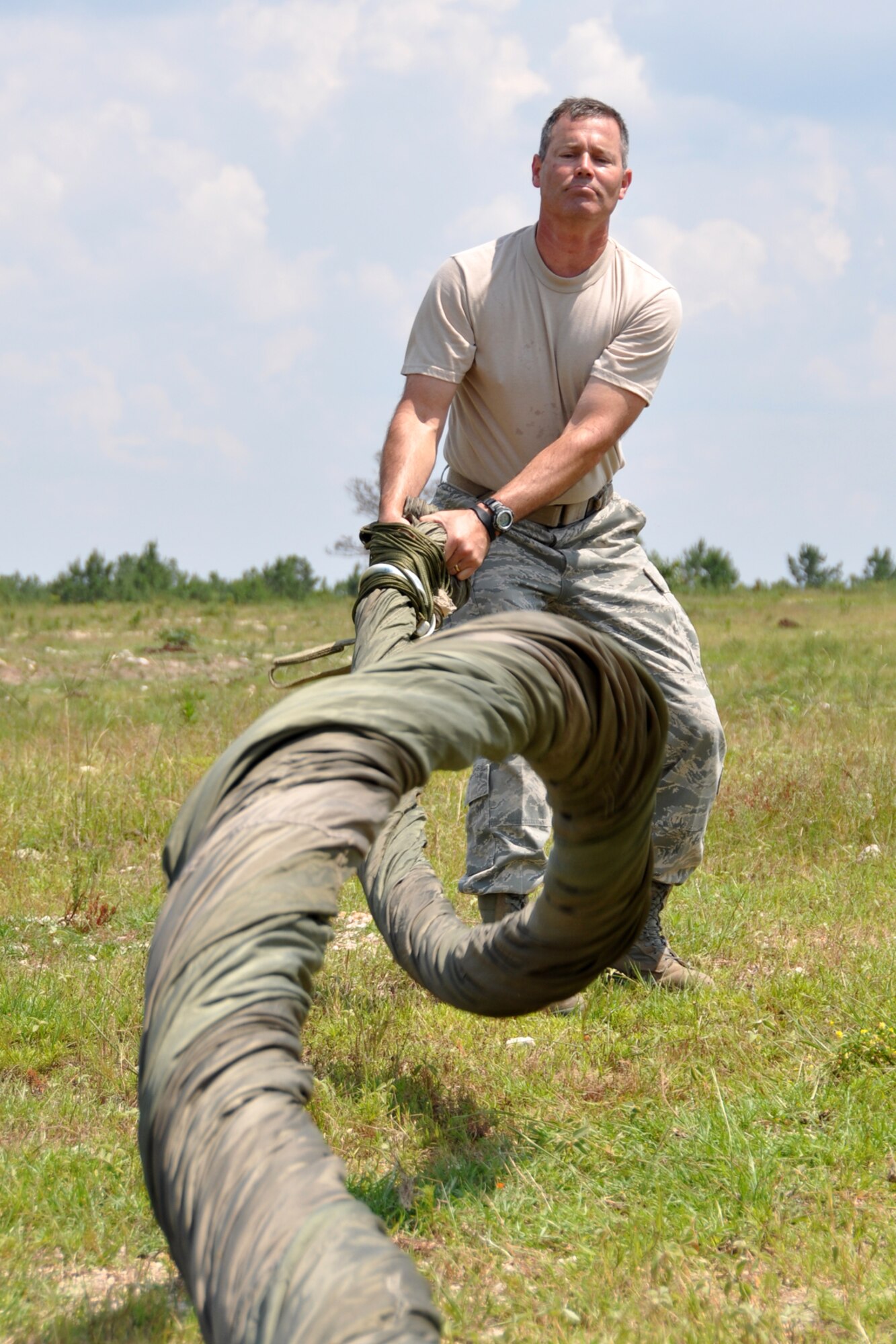 Tech. Sgt. Mike Fuller, a parachute rigger assigned to the 308th Rescue Squadron, Patrick  Air Force Base, Fla., performs a cigarette roll on a G-12 canopy in the field at Fort Polk, La., May 16, 2012. The cigarette roll allows for easier field storage and transportation of large canopies after they are used in heavy equipment parachute drops. Fuller, who was supporting the Patriot Saint exercise, was performing the cigarette roll on a 60 foot diameter canopy. (U.S. Air Force photo by Master Sgt. Jeff Walston/Released)