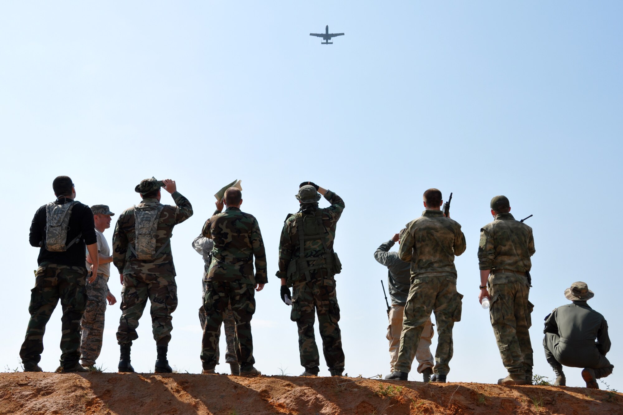 Members of the OPFOR (Opposing Force) unit watch an A-10 Thunderbolt II from the 47th Fighter Squadron, Barksdale Air Force Base, La., pass overhead just before the day’s events begin at Fort Polk La., May 16, 2012. The Airmen were part the Patriot Saint exercise, which is designed to hone the war fighting-skills of Air Force pararescuemen for deployment. The exercise also provided A-10 pilots with additional training in executing a search and rescue mission. (U.S. Air Force photo by Master Sgt. Jeff Walston/Released)
