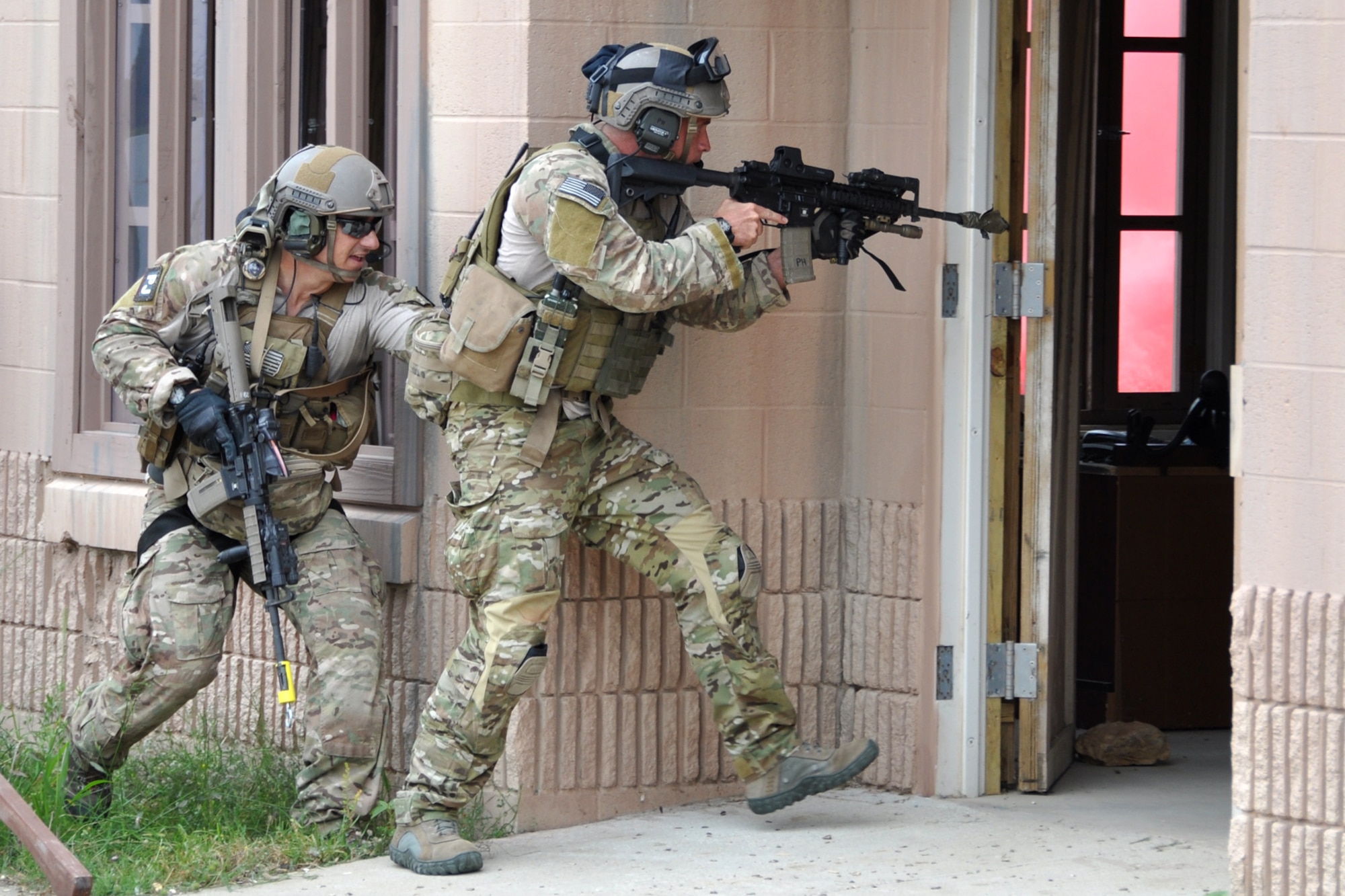 Two pararescuemen enter a building in a simulated village to clear it before advancing to rescue an American soldier at the Fort Polk Combined Arms Training Facility City Complex at Fort Polk, La., May 15, 2012. The Airmen were part of a combat search and rescue (CSAR) mission to rescue a soldier from hostile forces in support of the Patriot Saint exercise. (U.S. Air Force photo by Master Sgt. Jeff Walston/Released)  