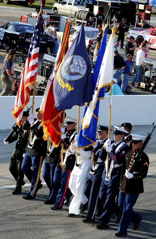 A joint-service color guard marches in formation during Military Appreciation Night at the Langley Motor Speedway in Hampton Va. May 19. U.S. Coast Guard Lt. Michelle Schopp sang the national anthem during the posting of the colors. (U.S. Air Force photo by Airman 1st Class Austin Harvill/Released) 