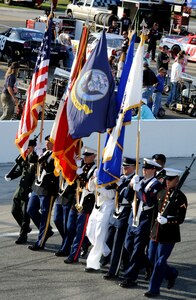 A joint-service color guard marches in formation during Military Appreciation Night at the Langley Motor Speedway in Hampton Va. May 19. U.S. Coast Guard Lt. Michelle Schopp sang the national anthem during the posting of the colors. (U.S. Air Force photo by Airman 1st Class Austin Harvill/Released) 