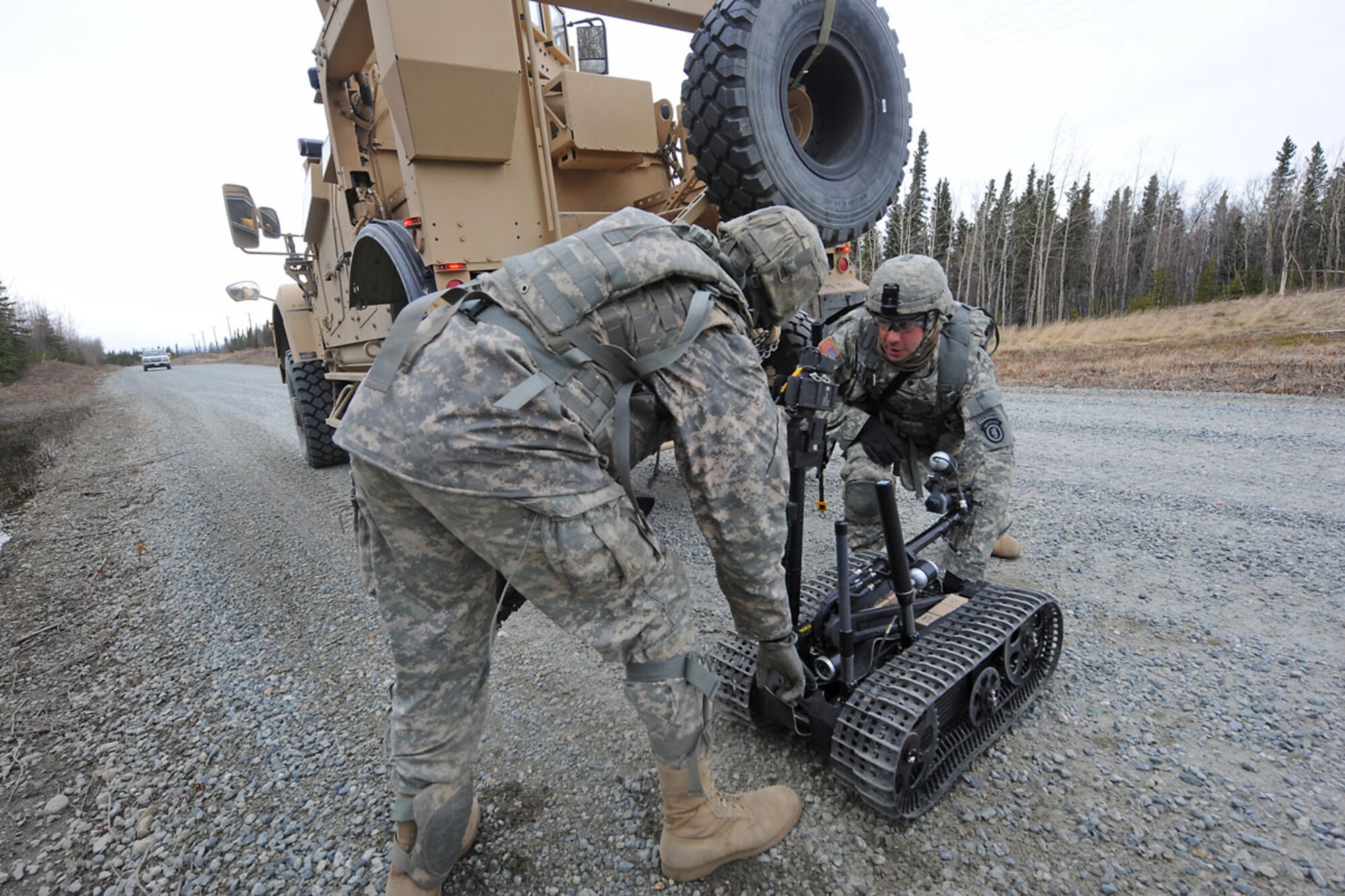 DONNELLY TRAINING AREA, Alaska -- Specialist Zachary Tabor, right, and Specialist Marcus Mincy load a tallon robot into the lead gun truck during a movement for a simulated route-clearance mission May 10. Loading it into the lead gun truck helps minimize time on the ground for the Soldiers. The 84th Engineer Support Company, 6th Engineer Battalion, Joint Base Elmendorf-Richardson, whose specialty was not clearing roadways for convoys, has been tasked to reshape their forces for a route-clearing mission. Their new job is to now go out searching for and investigating any roadside bombs or mines so that others may pass through quickly and safely. Tabor and Mincy are both heavy equipment operators with the 84th ESC (ABN).(U.S. Air Force photo by Staff Sgt. Cynthia Spalding)