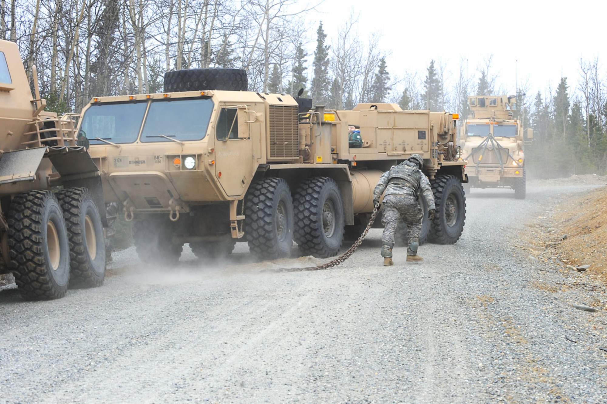 DONNELLY TRAINING AREA, Alaska -- Specialist James Clark removes a chain after a vehicle recovery during a movement for a simulated route-clearance mission May 10. The 84th Engineer Support Company, 6th Engineer Battalion, Joint Base Elmendorf-Richardson, whose specialty was not clearing roadways for convoys, has been tasked to reshape their forces for a route-clearing mission. Their new job is to now go out searching for and investigating any roadside bombs or mines so that others may pass through quickly and safely. Clark is a maintainer with the 84th ESC (ABN). (U.S. Air Force photo by Staff Sgt. Cynthia Spalding)