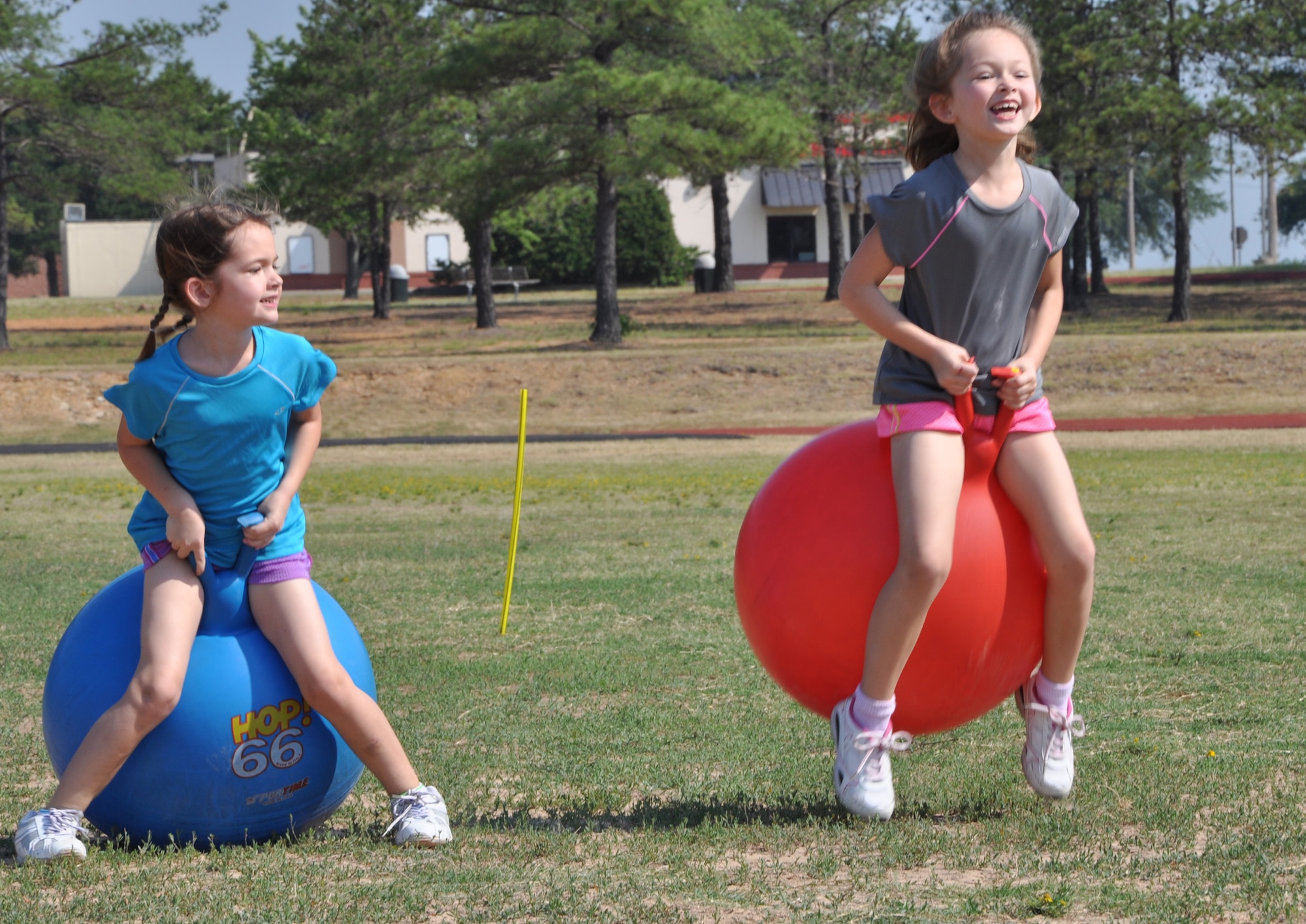 Eloise Brown, 5, and her sister Cece, 6, race against each other on bouncy balls during kid's Field Day at the Warfit Track May 19, 2012, at Little Rock Air Force Base, Ark. The field day lasted from 9 a.m. - 12 p.m., and ended with a race around the track. (U.S. Air Force photo by Staff Sgt. Jacob Barreiro)