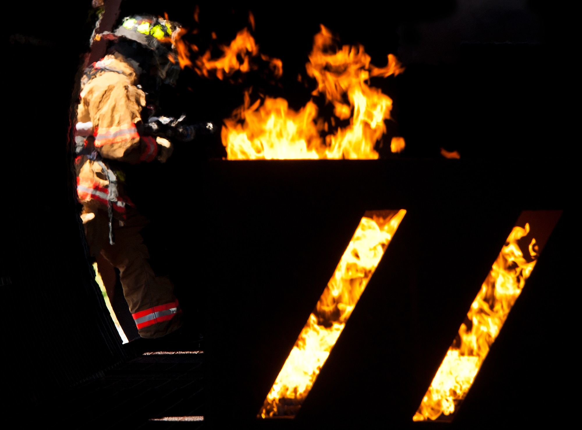 A firefighter enters the aircraft from the wing to battle a fire in the tail section during a live-fire exercise at Eglin Air Force Base, Fla.  The aircraft fire training is a yearly requirement for Eglin’s Airmen and civilian firefighters.  The firefighters must battle a fire on the inside and outside of the aircraft to complete the training.  (U.S. Air Force photo/Samuel King Jr.)