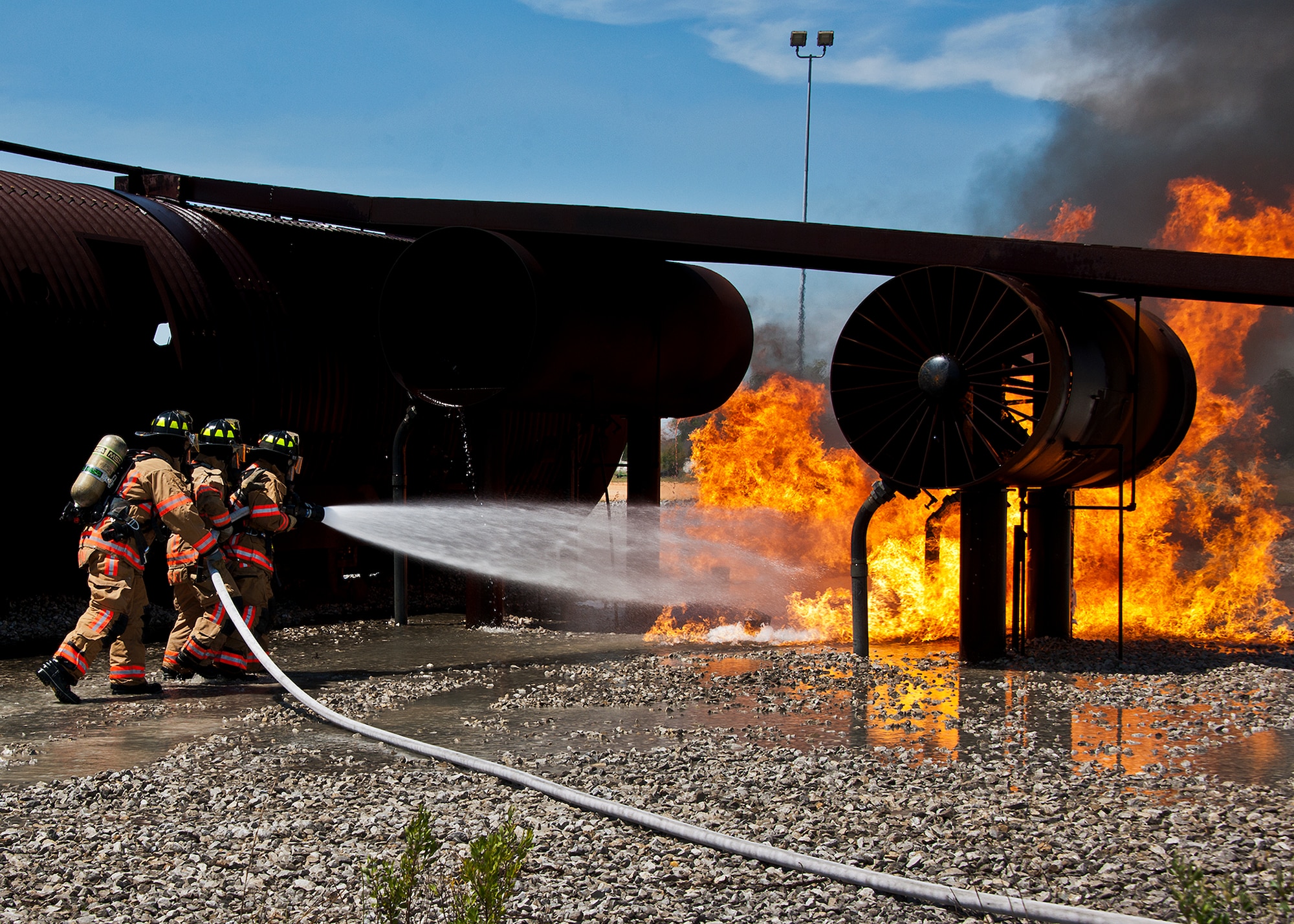 A team of three firefighters move toward the flames on the engine of an aircraft during a live-fire exercise at Eglin Air Force Base, Fla.  The aircraft fire training is a yearly requirement for Eglin’s Airmen and civilian firefighters. The firefighters must battle a fire on the inside and outside of the aircraft to complete the training.   (U.S. Air Force photo/Samuel King Jr.)