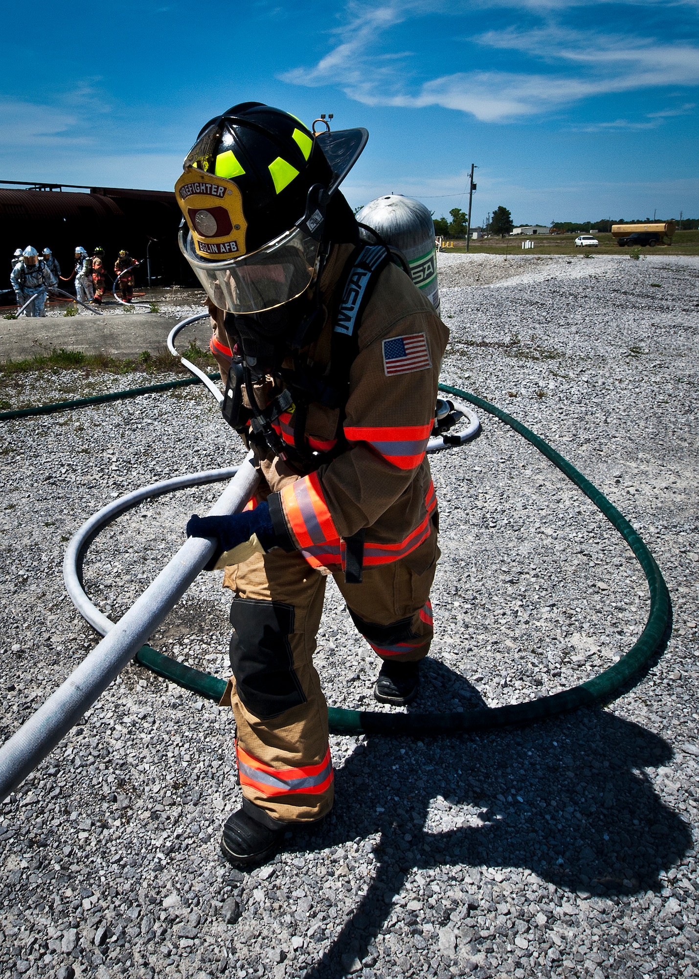 A firefighter pulls a hose back out of the burn pit after battling a controlled fire on the wing and nose of the aircraft at Eglin Air Force Base, Fla.  The aircraft fire training is a yearly requirement for Eglin’s Airmen and civilian firefighters. The firefighters must battle a fire on the inside and outside of the aircraft to complete the training.   (U.S. Air Force photo/Samuel King Jr.)