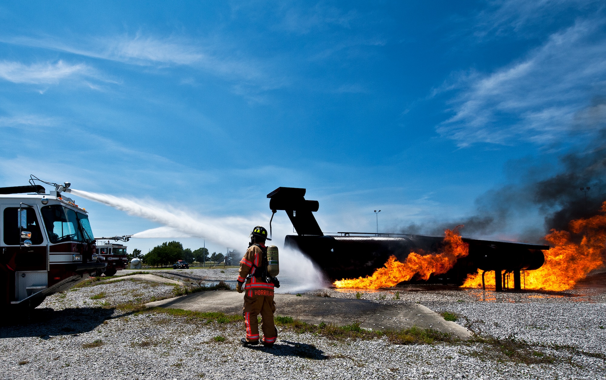 Sean Horrigan, of the 96th Civil Engineer Squadron, monitors firefighters’ progress as they battle a controlled aircraft fire from their fire engines at Eglin Air Force Base, Fla.  The aircraft fire training is a yearly requirement for Eglin’s Airmen and civilian firefighters.  The firefighters must battle a fire on the inside and outside of the aircraft to complete the training.  (U.S. Air Force photo/Samuel King Jr.)