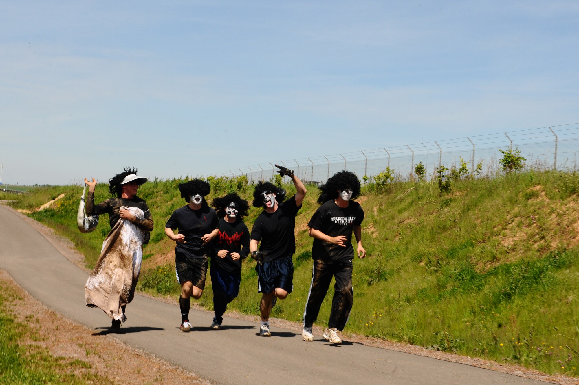 SPANGDAHLEM AIR BASE, Germany – Members from Team Kiss and a Groupie approach the finish line during the Tier II Mud-Run outside base here May 17. The mud-run consisted of 17 teams, which ran five kilometers through various obstacles and competed for best costumes. The event raised more than $2,000 for the Wounded Warrior Project in Landstuhl. (U.S. Air Force photo by Airman 1st Class Dillon Davis/Released)