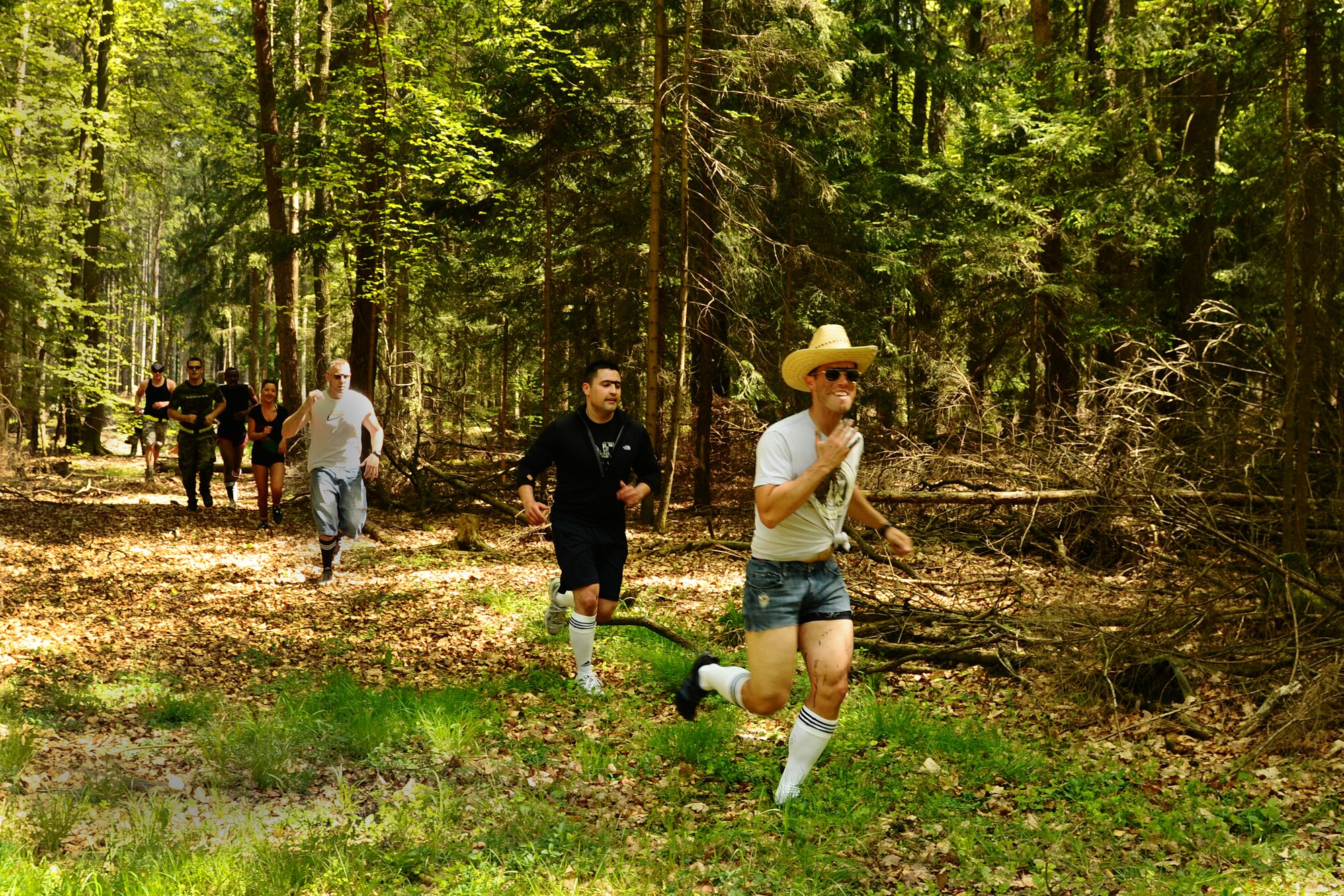 SPANGDAHLEM AIR BASE, Germany -- Team The Unis members run through the forest during the Tier II Mud-Run outside base here May 17. The mud-run consisted of 17 teams, which ran five kilometers through various obstacles and competed for best costumes. The event raised more than $2,000 for the Wounded Warrior Project in Landstuhl. (U.S. Air Force photo by Airman 1st Class Dillon Davis/Released)