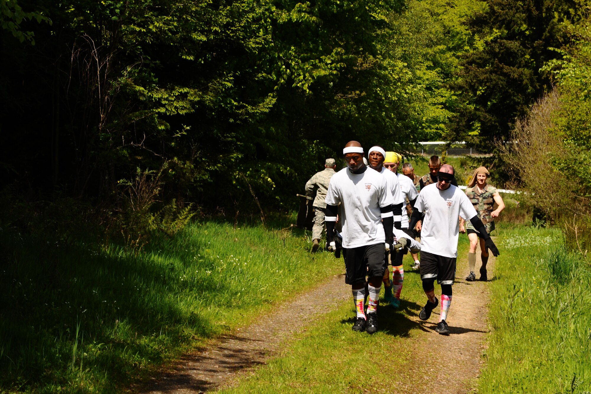 SPANGDAHLEM AIR BASE, Germany -- Team Mud Monkeys carry a team member uphill using a litter during the Tier II Mud-Run outside of base here May 17. The mud-run consisted of 17 teams, which ran five kilometers through various obstacles and competed for best costumes. The event raised more than $2,000 for the Wounded Warrior Project in Landstuhl. (U.S. Air Force photo by Airman 1st Class Dillon Davis/Released)