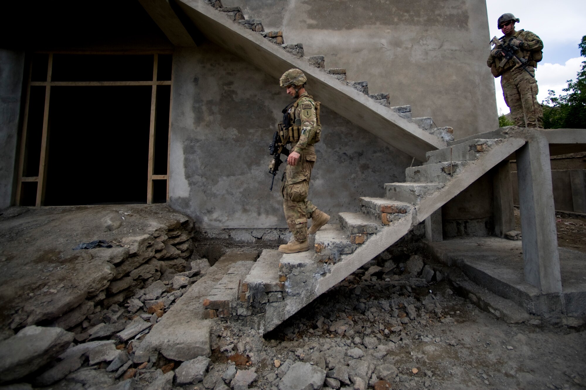 U.S. Air Force Tech. Sgt. Richard Love with Provincial Reconstruction Team Kapisa walks down a set of stairs at a local school during an inspection while Sgt. 1st Class Shannon Davis provides security, Kapisa Province, May 17, 2012. The Kapisa PRT is a U.S. military team that engages with local leaders and contractors to plan and inspect development projects in the province. (U.S. Air Force photo by Staff Sgt. Greg C. Biondo)(Released)