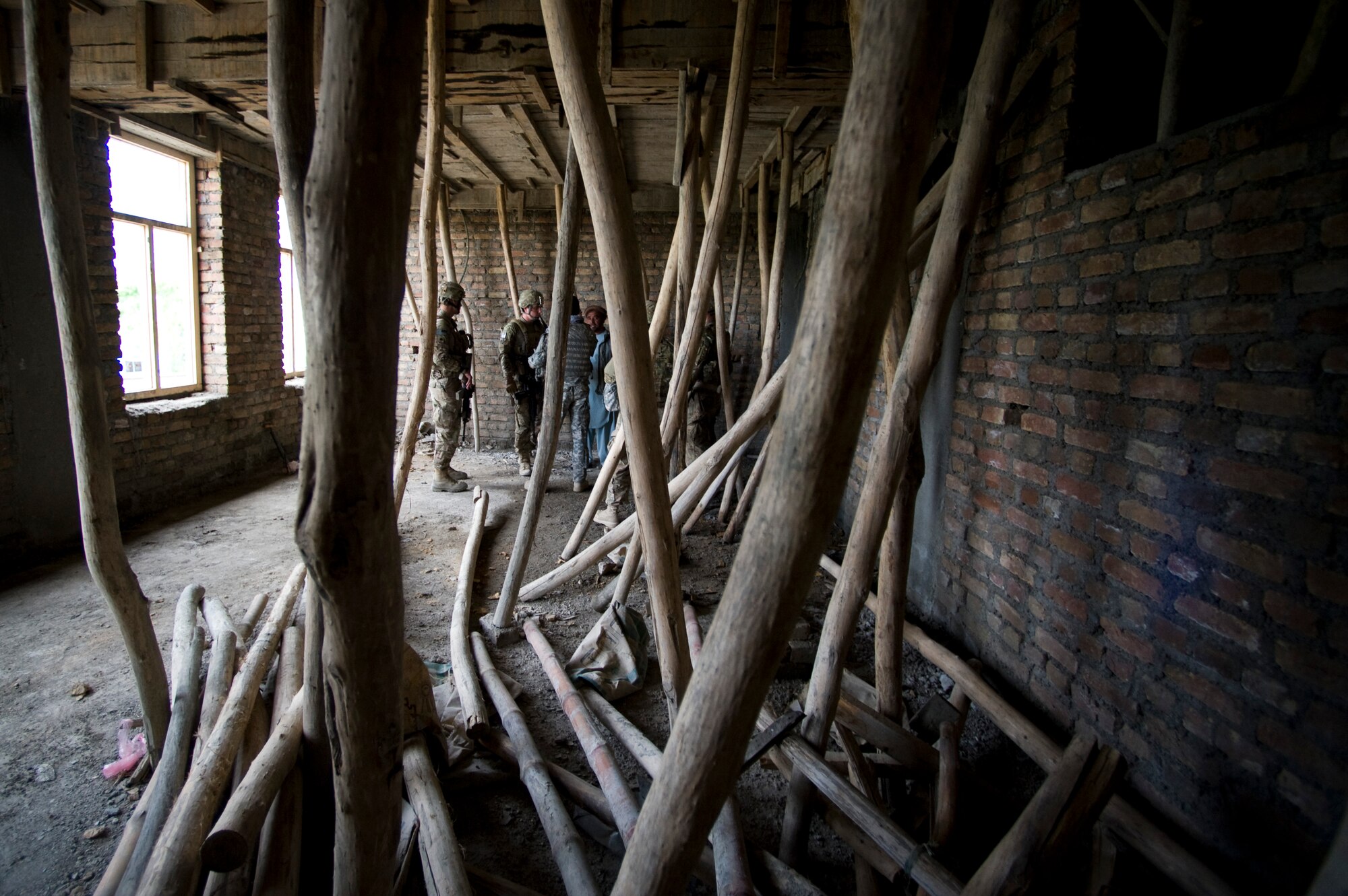 Logs hold up the roof of an under construction school while members of Provincial Reconstruction Team Kapisa talk to a local contractor about his progress with the project, Kapisa Province, Afghanistan, May 17, 2012. The Kapisa PRT is a U.S. military team that engages with local leaders and contractors to plan and inspect development projects in the province. (U.S. Air Force photo by Staff Sgt. Greg C. Biondo)(Released)