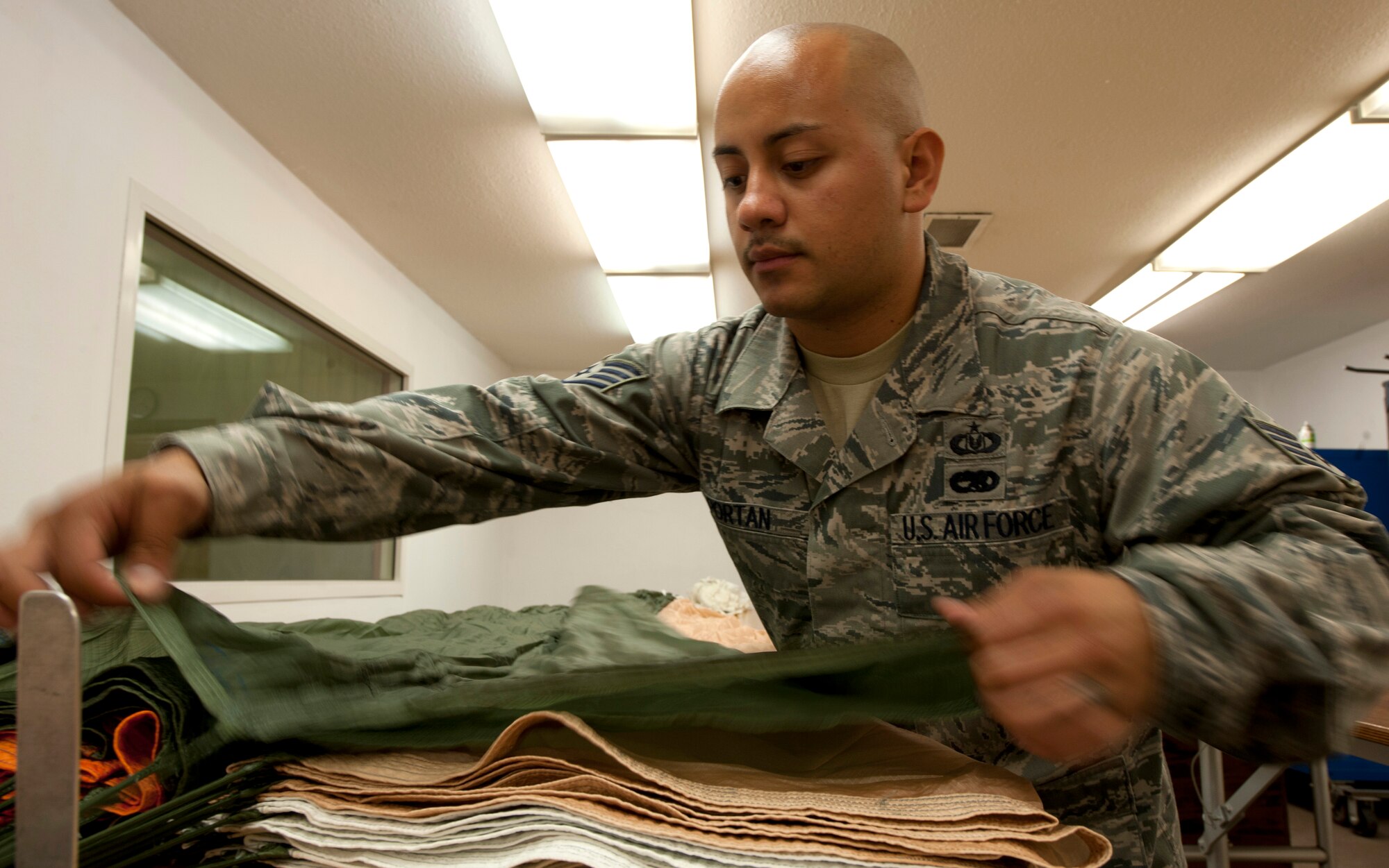 U.S. Air Force Staff Sgt. Edwin Portan, 379th Expeditionary Operations Support Squadron non-commissioned officer in-charge, prepares the BA-22 parachute to be repacked after conducting an inspection May 17, 2012. The inspection is to recertifies the life cycle of the parachute and must be 100% serviceable at all times. Portan is deployed from Eglin Air Force Base, Fla., and is a native of Los Angeles. (U.S. Air Force photo/Staff Sgt. Sheila deVera)