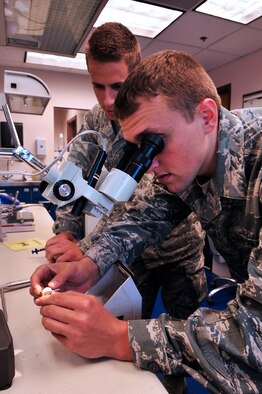 U.S. Air Force Senior Airman Justin Rhodes and Airman 1st Class Collin Casey, both dental lab technicians assigned to the 20th Dental Squadron, inspect an unsealed crown at Shaw Air Force Base, S.C., May 15, 2012.(U.S. Air Force photo by Airman Nicole Sikorski/Released) 
