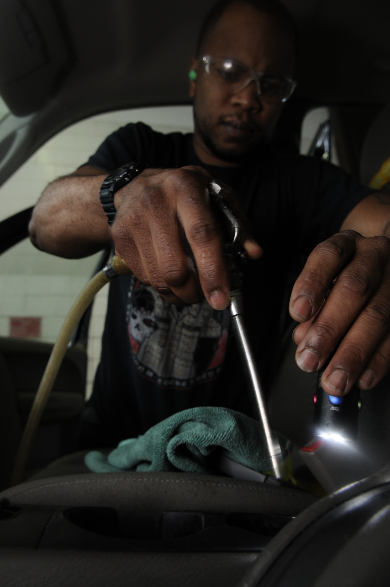 SPANGDAHLEM AIR BASE, Germany – Demetrius Clark, auto hobby center vehicle detailer, shines a light into a vehicle’s cup holder to spot dirt and debris he can spray away with an air-gun during an agricultural car cleaning and detailing May 15 at the auto hobby center here. Clark is cleaning this vehicle to prepare it for a personal owned vehicle agricultural inspection, which is required to ship vehicles to the States. The auto hobby center provides cleaning services that guarantee vehicles pass the agricultural inspection as well as other cleaning and detailing services to base members. (U.S. Air Force photo by Senior Airman Natasha Stannard) 