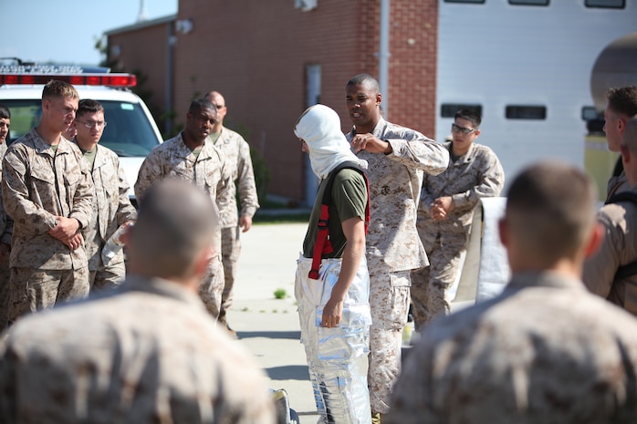 Sgt. David Bryant (center), an aircraft rescue and firefighting specialist with 2nd Marine Aircraft Wing, uses Pfc. Cameron D. McDonald, a bulk fuel specialist with Bulk Fuel Company, 8th Engineer Support Battalion, 2nd Marine Logistics Group, to show the proper way to assemble the fire proximity suit during a training exercise aboard Marine Corps Air Station Cherry Point, N.C., May 22, 2012. The Marines also received a brief on responsibilities as a firefighter and a class on how to use the different hoses and nozzles.  The training culminated with troops applying lessons learned and extinguishing four different controlled-fuel fires.