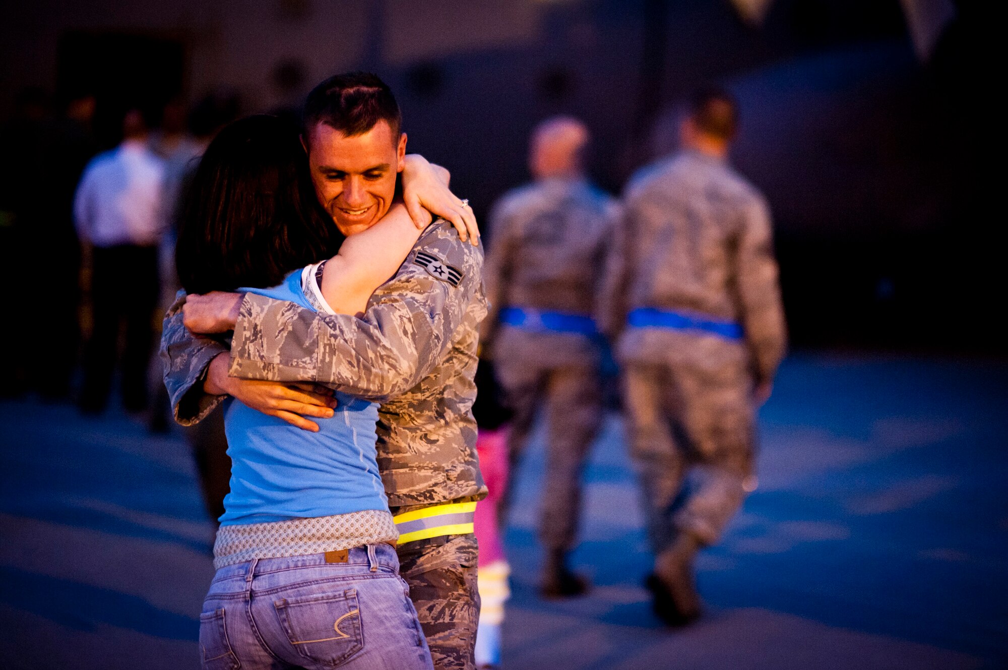 YOKOTA AIR BASE, Japan -- Senior Airman Kyle Velasco, center, 374th Aircraft Maintenance Squadron aerospace propulsion journeyman, hugs his wife, Lindsey, at Yokota Air Base, Japan, May 19, 2012. This was their first reunion in four months following his deployment to Southwest Asia. (U.S. Air Force photo by Staff Sgt. Samuel Morse)