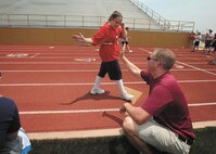 Tech. Sgt. Lawrence Snyder, 743rd Intelligence Support Squadron, cheers on Special Olympian Alicia Guevara as she crosses the finish line during the 100-meter run May 5 at Harlandale Memorial Stadium. (U.S. Air Force photo/Robbin Cresswell)