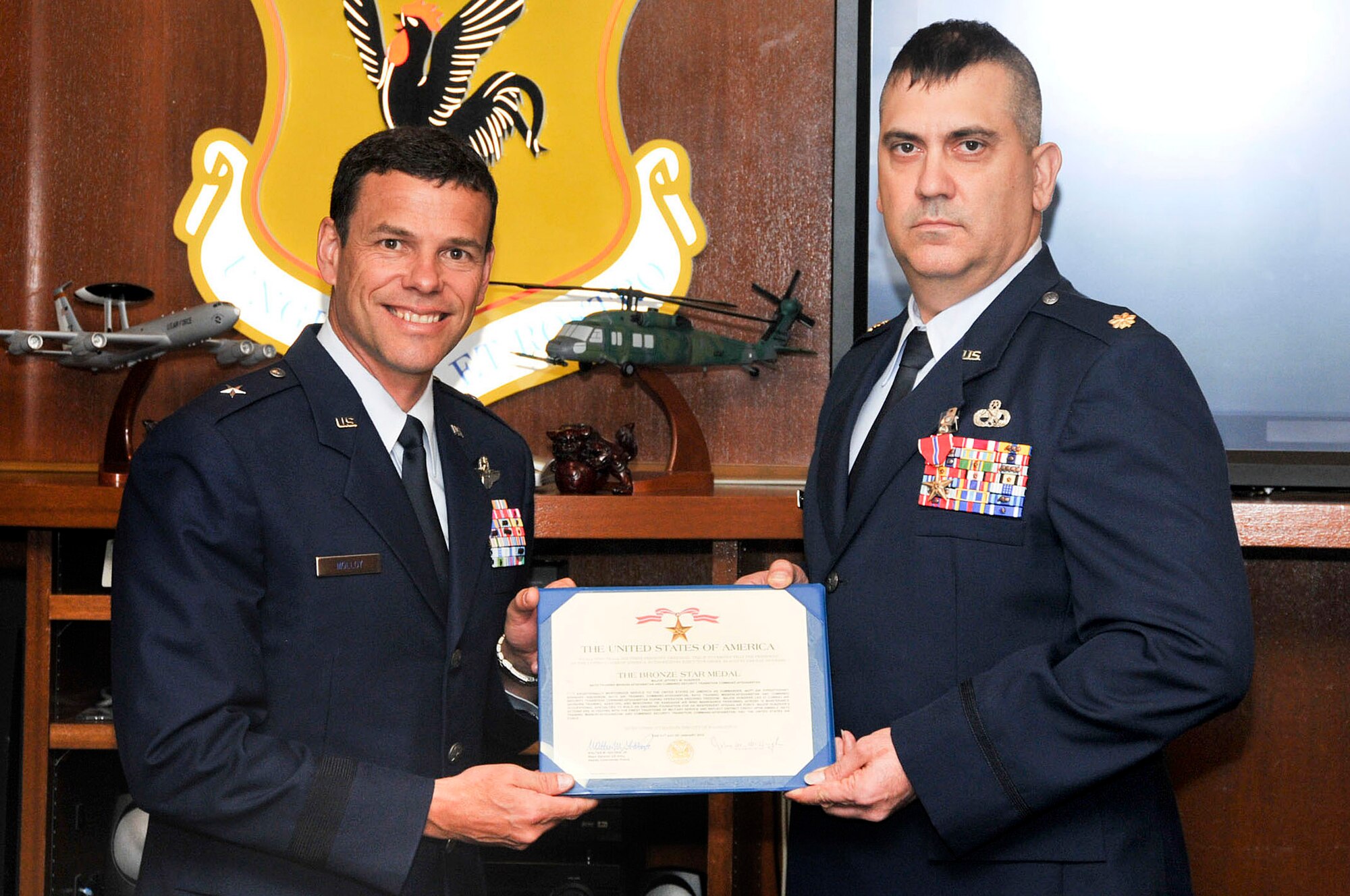 U.S. Air Force Brig. Gen. Matt Molloy, 18th Wing commander, presents U.S. Air Force Maj. Jeffrey Hunziker, 718th Aircraft Maintenance Squadron, his Bronze Star Medal citation during the Kadena Team staff meeting on Kadena Air Base, Japan, May 21, 2012. Hunziker received the Bronze Star for his meritorious service as commander of the 442nd Air Expeditionary Advisory Squadron at Kandahar Air Field, Afghanistan. (U.S. Air Force photo/Staff Sgt. Darnell T. Cannady)