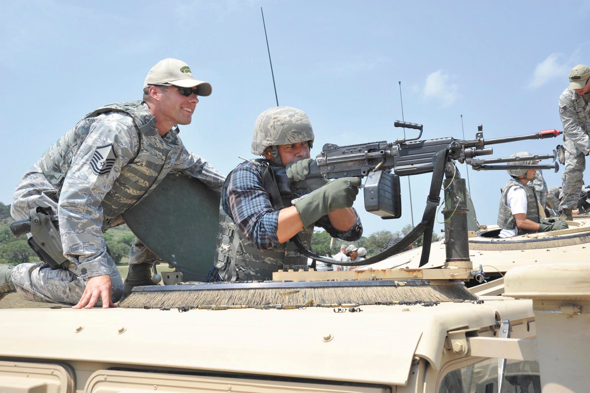 Master Sgt. Brandon Hannasch, flight chief, Basic Officer Course, guides actor Jon Huertas as he lays down a burst of suppressive fire from an M249 machine gun during a simulated assault May 4 at Camp Bullis. (U.S. Air Force photo/Alan Boedeker)