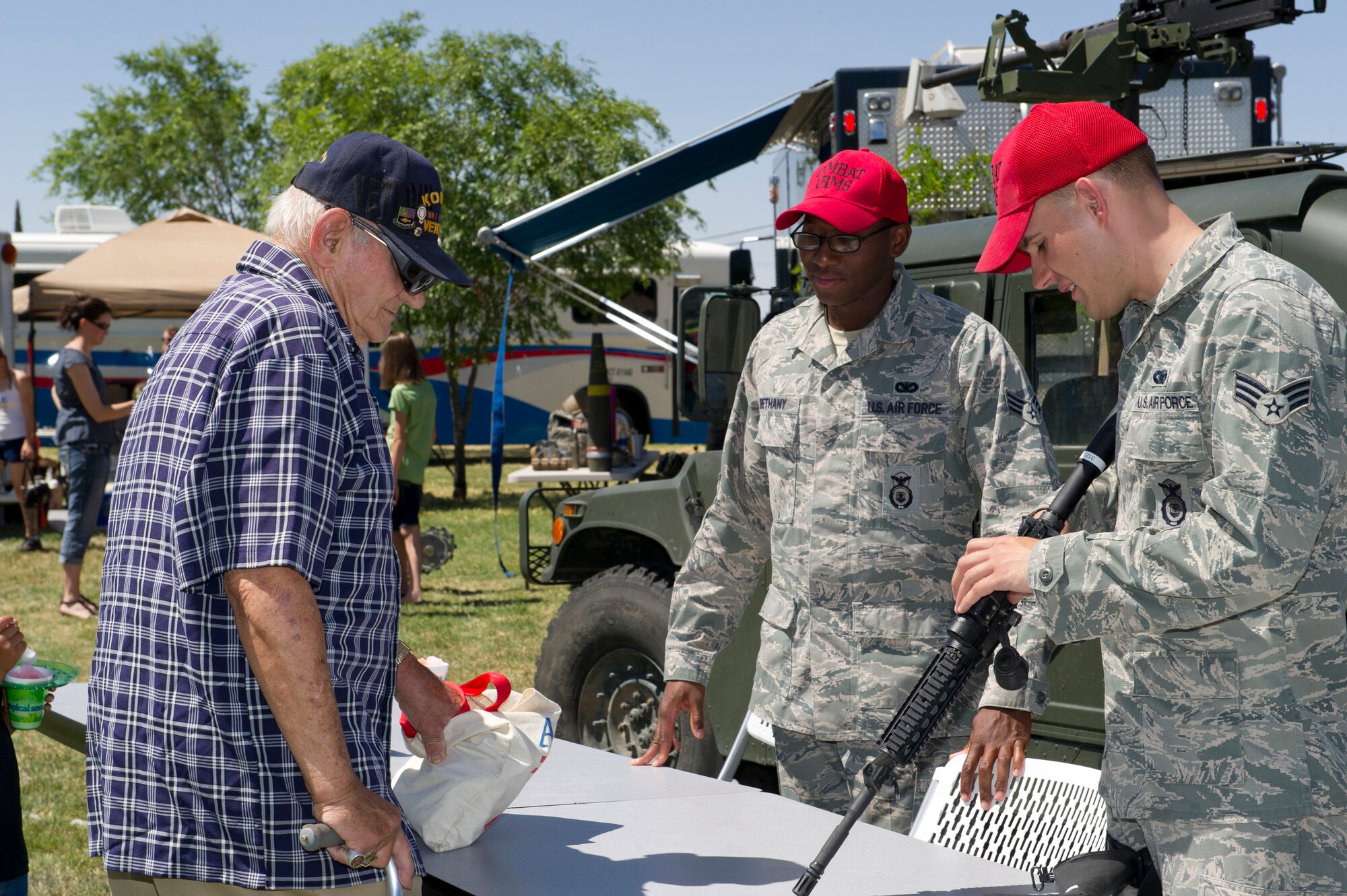 ALAMOGORDO, N.M.—Senior Airmen Terrance Bethany and Joseph Glover, both from the 49th Security Forces Squadron combat arms section, talk about the M4 carbine with John Cripe, a World War II and Korean War veteran, at the Alamogordo Armed Forces Day celebration at Washington Park May 19. The combat arms section was one of several units who supported the event with a display of weaponry, including the M4 carbine, the M239 and M240 machine guns. The event was designed to honor men and women who currently serve or have served in the military. (U.S. Air Force photo by 2nd Lt. Logan Clark/Released)