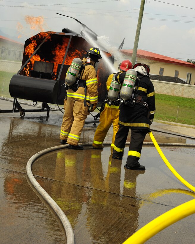 SOTO CANO AIR BASE, Honduras - Honduran firefighters put out a mock helicopter fire as a U.S. Air Force firefighter instructs the pair on the procedures during Central America Sharing Mutual Operational Knowledge and Experiences (CENTAM SMOKE) exercise at Soto Cano Air Base, Honduras, May 8, 2011. CENTAM SMOKE allows U.S. and Honduran firefighters four days of team-building training. (U.S. Air Force photo/Staff Sgt. Bryan Franks)